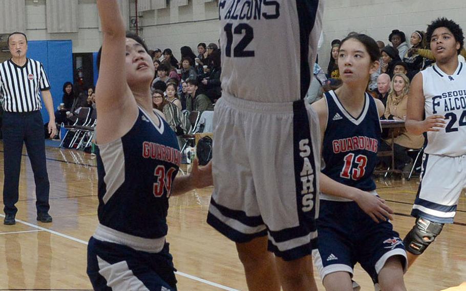 Seoul American center Ebony Dykes shoots between Yongsan's Rachael Ko and Andre Lee during Friday's final in the Korea Blue Division girls basketball tournament. The Falcons routed the Guardians 46-25.