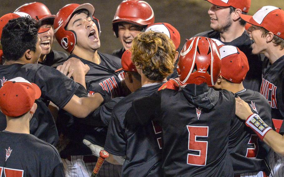 Nile C. Kinnick's Jonathan Acosta, third from left, and his teammates celebrate his home run against Yokota during the Red Devils' 9-2 victory in Tuesday's Kanto Plain baseball game.