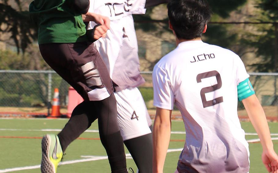 Daegu's David Spavins goes up to head the ball against Taejon Christian's Yisoo Han as Dragons teammate Hyunjoon Cho watches during Saturday's Korea Blue boys soccer match, won by the Dragons 1-0 on an own goal.