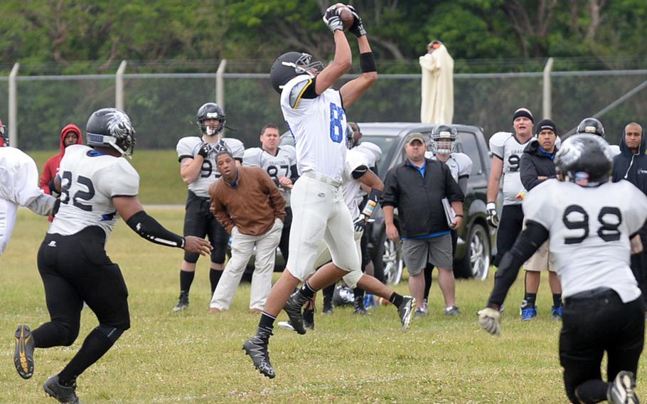 Hansen Outlaws Nick Jackson snares a catch between two Okinawa Dragons defenders during Saturday's USFJ-AFL game, won by the Outlaws 14-12.