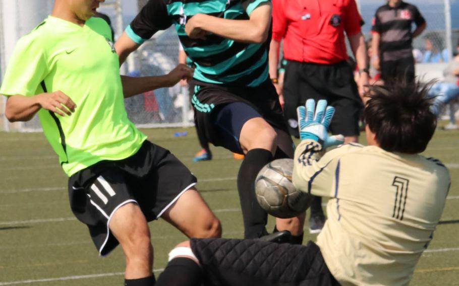 Nile C. Kinnick's Kai Sullivan is stopped on the attack by Matthew C. Perry keeper William Rudolph and defender Colin Ernst during Saturday's DODEA Japan boys soccer final. The Red Devils blanked the Samurai 6-0.