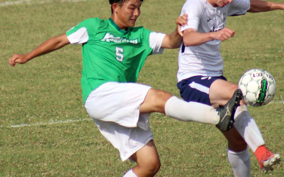Kubasaki's Kaisei Taylor boots the ball past Seoul American's Jeff Hindman during Monday's round-robin match in the Far East Division I boys soccer tournament. The Dragons won 5-0.
