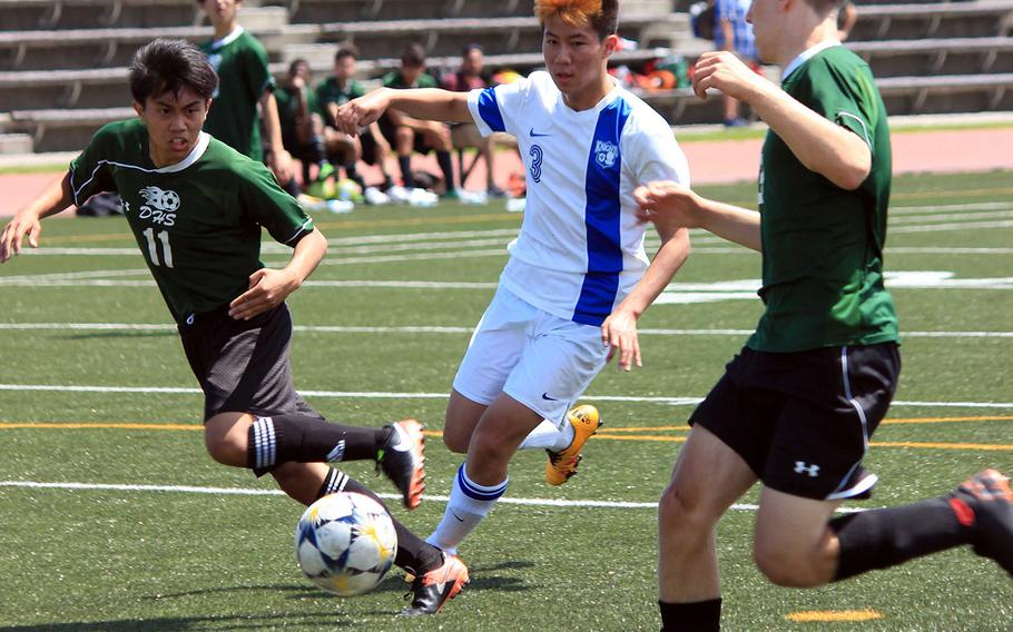 Christian Academy Japan's SeongJoon Park dribbles between Daegu defenders during Tuesday's playoff game in the Far East Division II boys soccer tournament. The Knights won 6-1.
