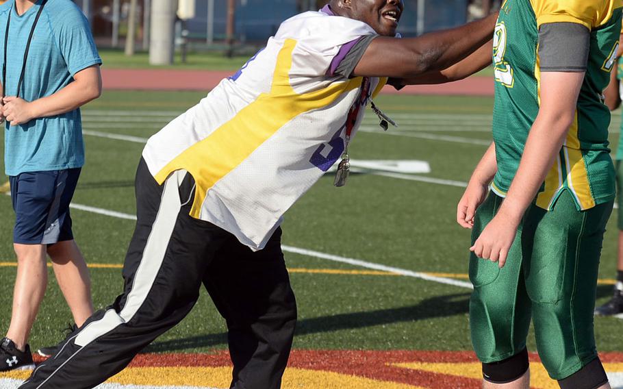 Eagles coach Jeremy Sanders demonstrates a blocking technique to lineman Caleb Struve.