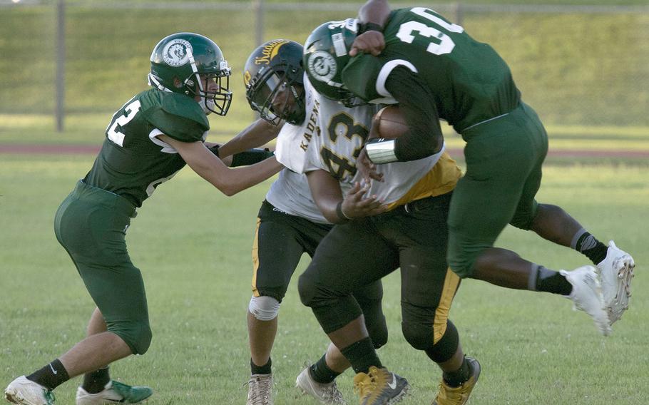 Kadena running back Uriah Morris gets turned sideways by Kubasaki's defense, led by Keith Rascoe, right.