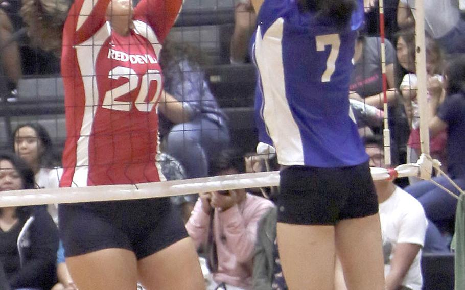 Nile C. Kinnick's Madelyn Gallo and Christian Academy Japan's Keziah Sou battle at the net for the ball during the Knights' five-set win Tuesday over the Red Devils.