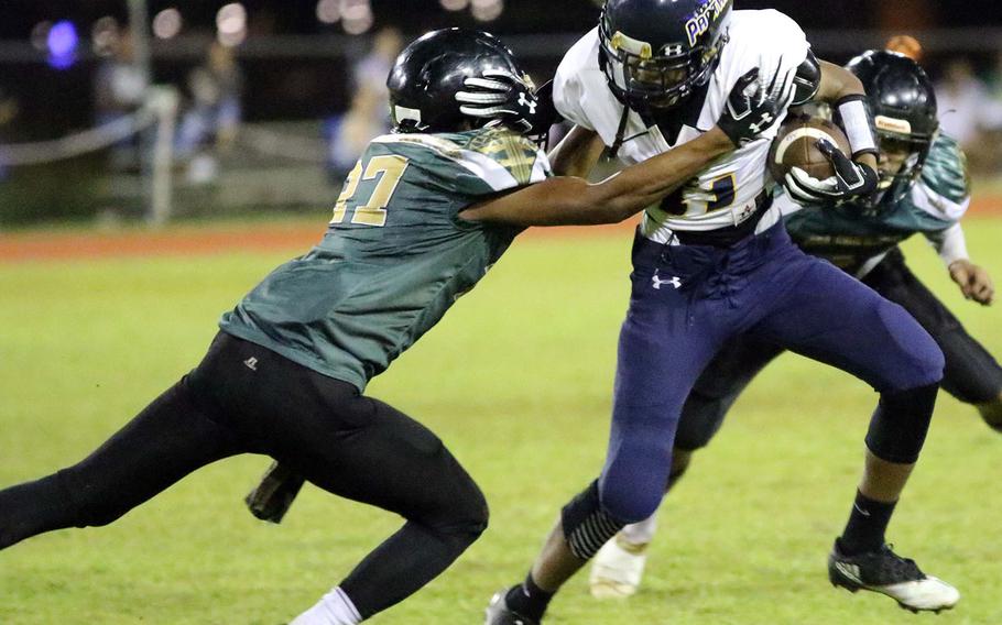 Guam High's Elijah Ferrell-Ayers tries to avoid the tackle of John F. Kennedy's Jacobe Quinata.