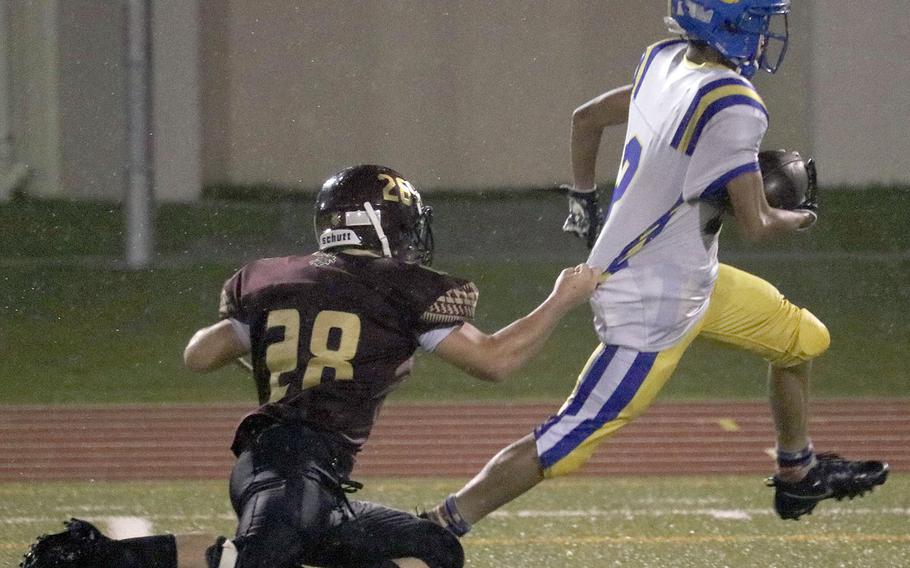 Matthew C. Perry defender Cameron Penn tries to slow Yokota running back Rashawn Wilcox by grabbing his shirt.