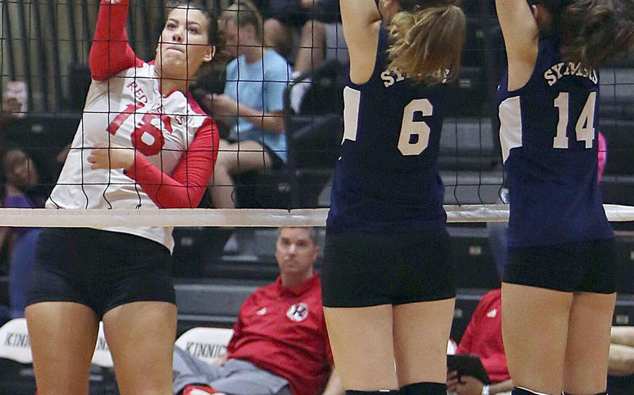 Nile C. Kinnick's Madelyn Gallo smacks a spike past Sacred Heart's Noe Shimojo and Maya Festenhausen during Thursday's three-set win by the Red Devils over the Symbas.