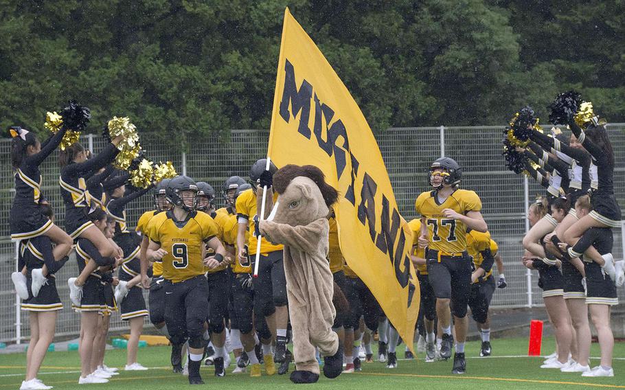 Flanked by cheerleaders, American School In Japan's football team takes the field for Saturday's Spirit Day game against Humphreys, won by the host Mustangs 28-12.