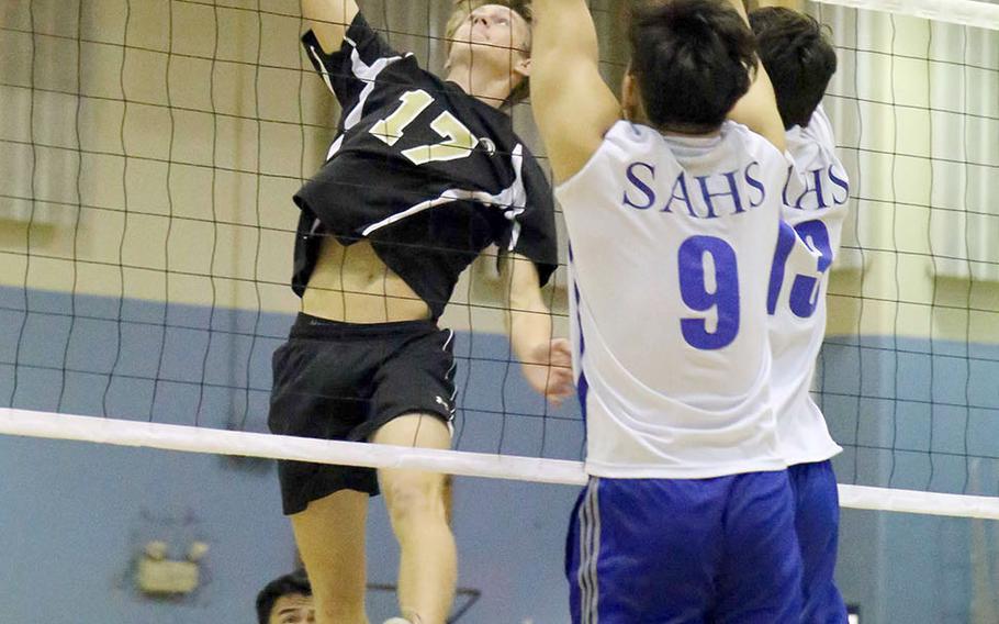 Humphreys' Connor Coyne skies for a spike against Brian Choe and Timothy Stewart of Seoul American during Wednesday's three-set win by the Blackhawks over the Falcons.