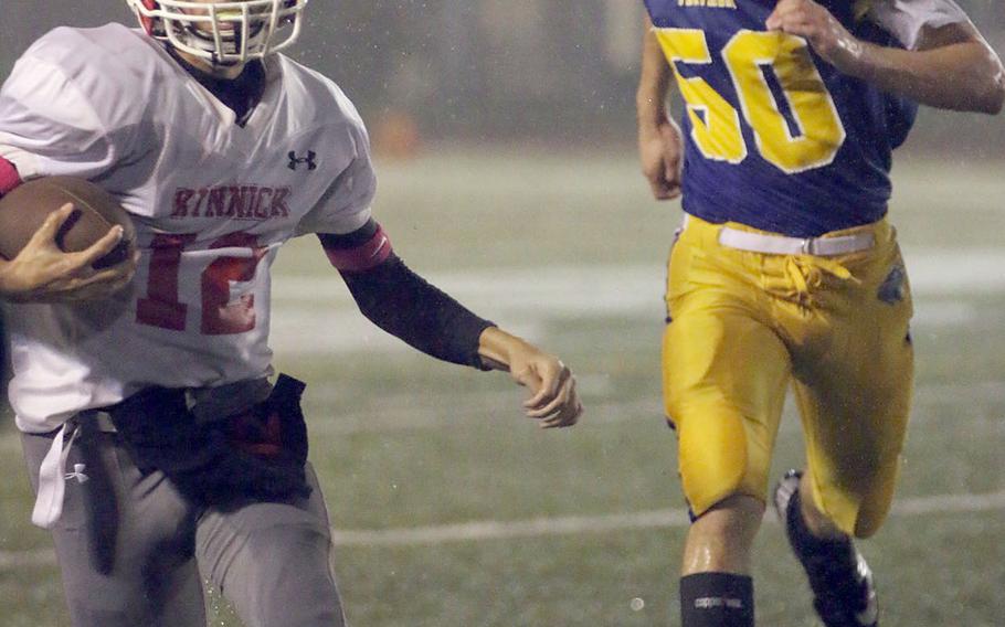 Nile C. Kinnick quarterback Patrick Kelly races for yardage ahead of Yokota's Austin Fisher.