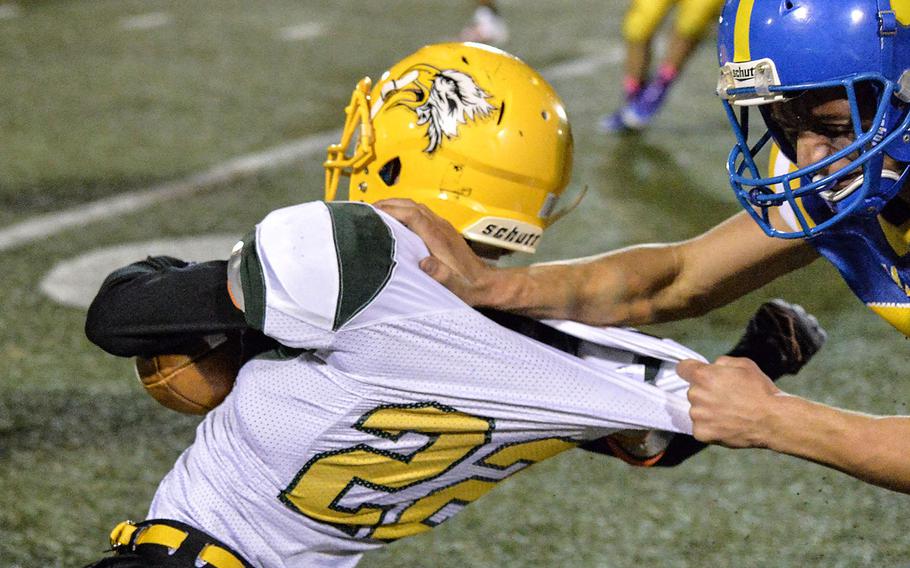 A Yokota defender gets hold of the jersey of Robert D. Edgren running back Douglas Tankney.