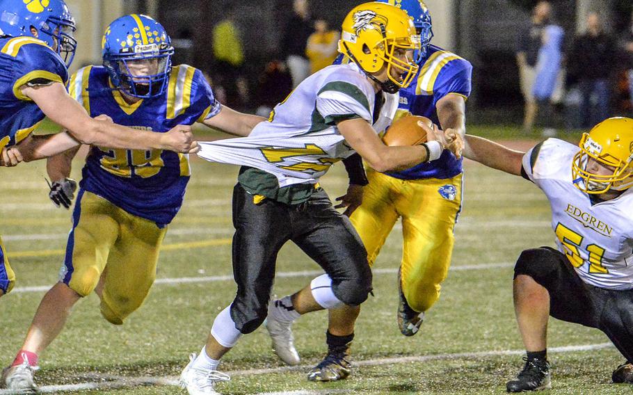 Yokota defenders stretch the jersey of Robert D. Edgren quarterback Raphael Lykins.