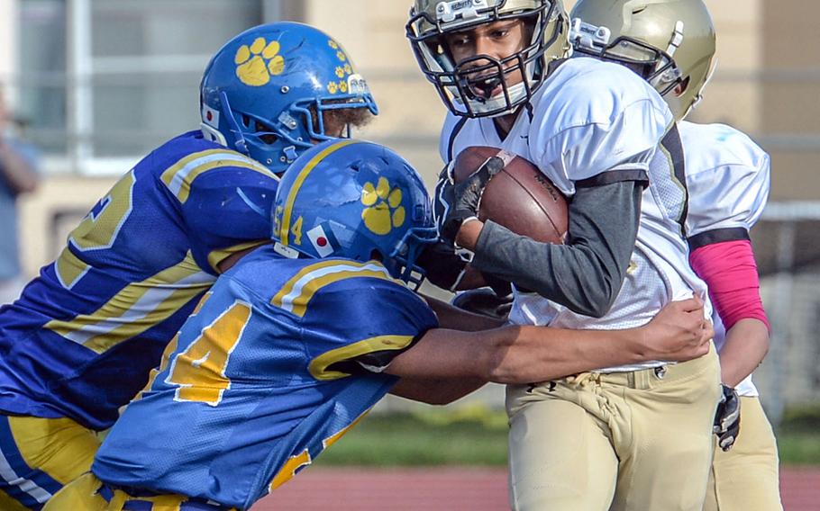 Humphreys quarterback Miles Brice tries to run past two Yokota tacklers.