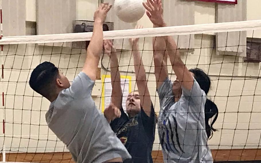 Osan spikers Maddie Taylor and Maja Inthavixay go through blocking drills with Cougars assistant coach and base team player Josh Aguirre during practice Wednesday. Osan hosts the KAIAC Plate tournament Friday and Saturday.