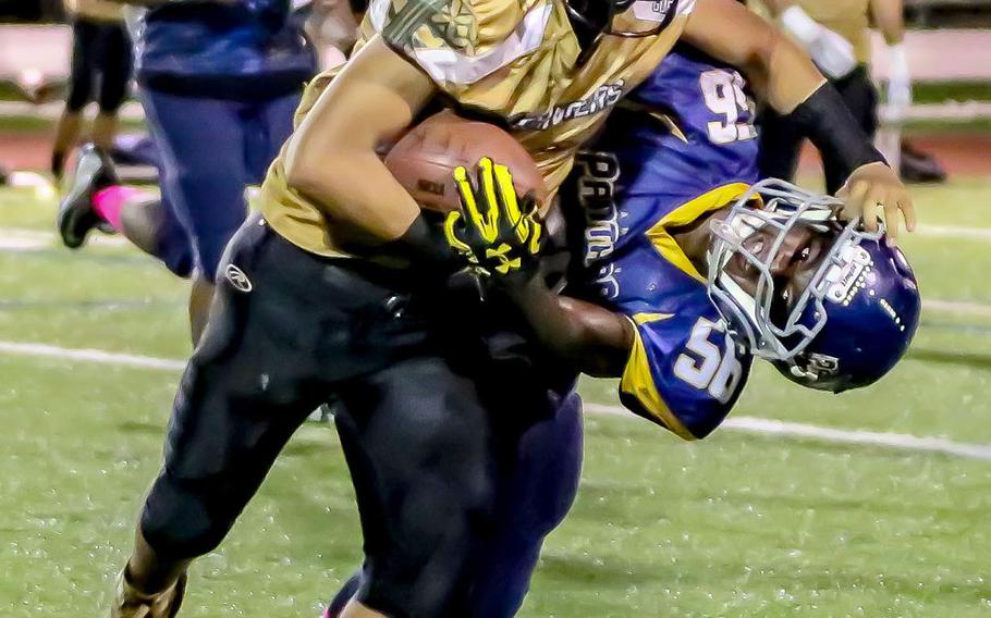 John F. Kennedy's Andrew Perez tries to fight off the tackle of Guam High's Jeylyn Dowdell.