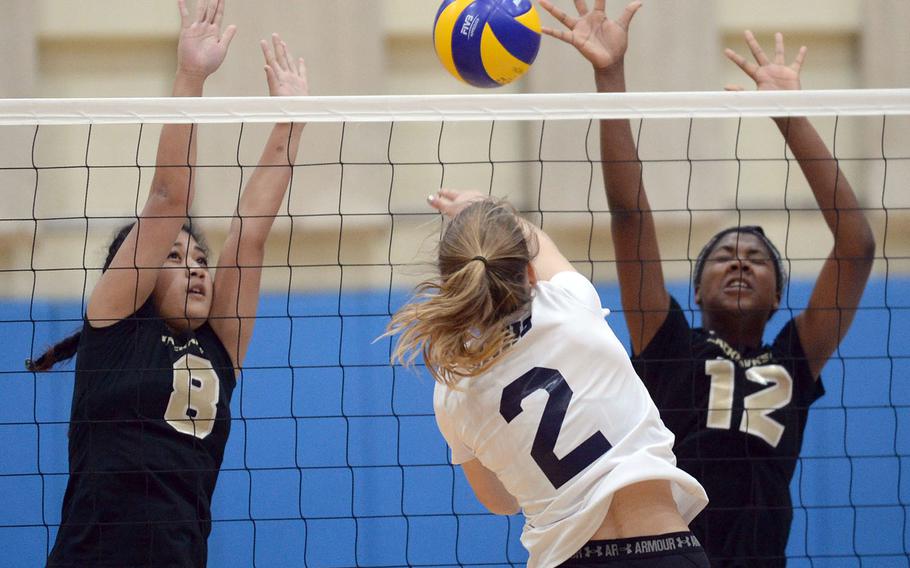 Seoul American's Olivia Kirschner rips the ball past Humphreys' double block of Alaina Areniego and Jayla Horne.