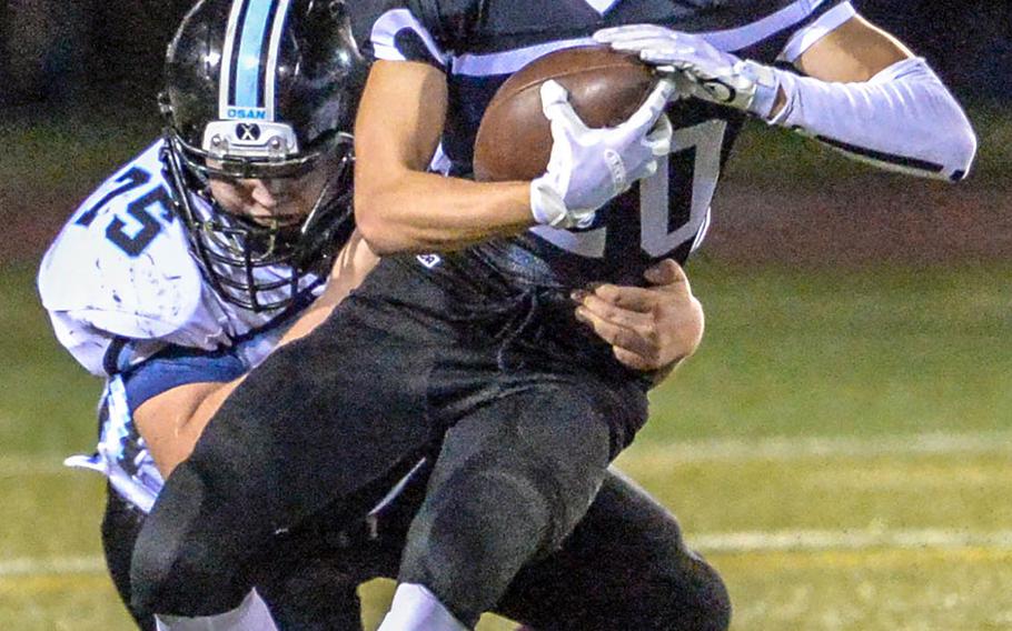 Zama running back Luke Singer gets wrapped up by Osan's Griffin Armstrong.