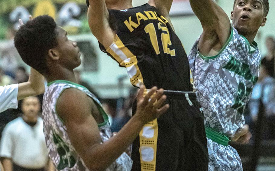 Kadena's Skyler King leaps to shoot between Kubasaki's Sam Gbatu and Damien Dorval during Friday's Okinawa boys basketball game. The Panthers won 72-53.