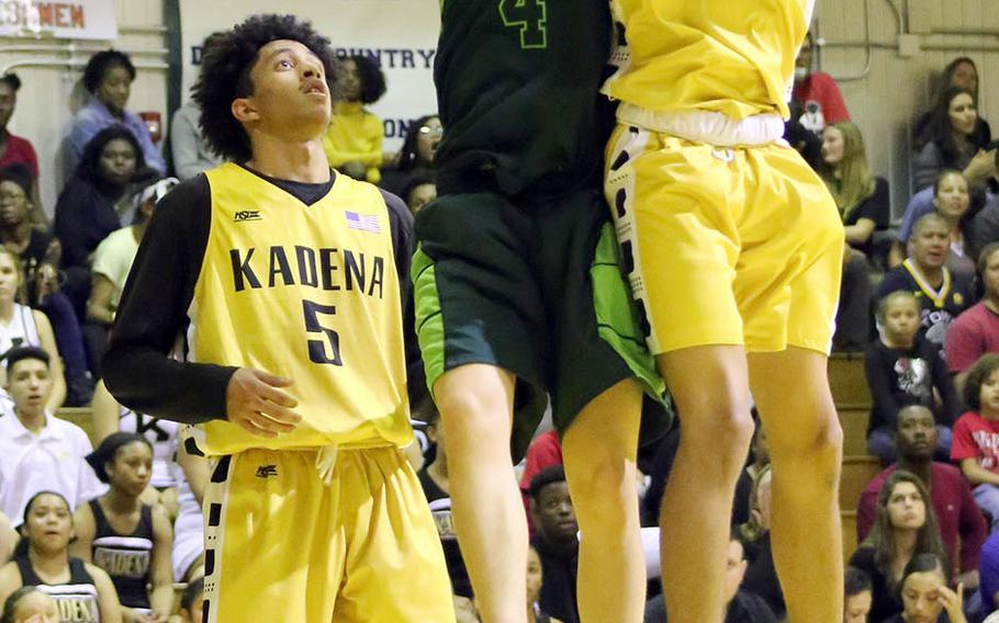 Kadena's Skyler King pulls down one of his 10 rebounds in front of Kubasaki's Mason Taylor during Friday's Okinawa boys basketball game. The Panthers won 57-48 to clinch their third straight season series and district title over the Dragons.