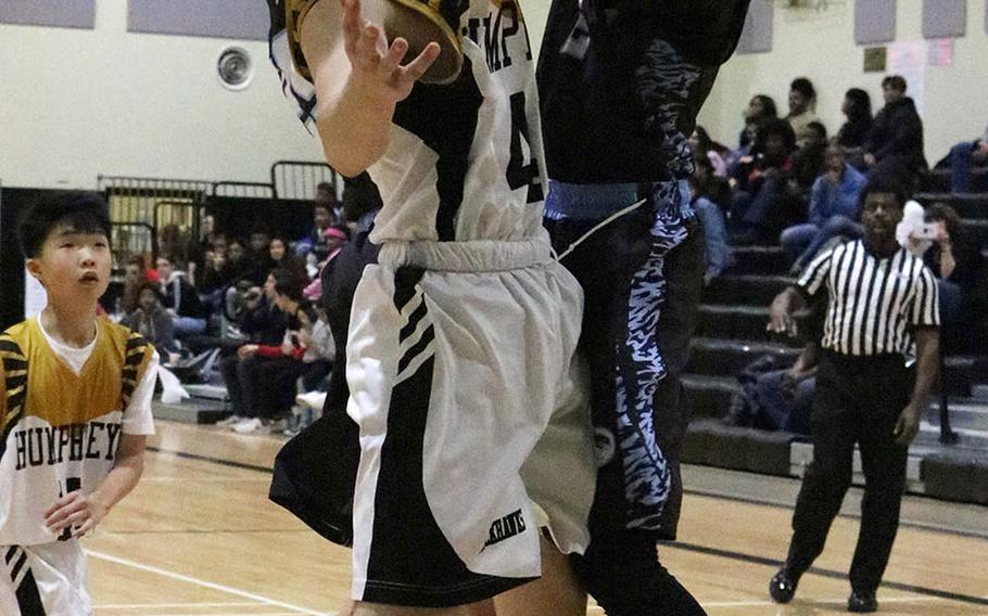 Humphreys' Cullen Areniego and Osan's Braden Snowman leap for the ball during Friday's Korea boys basketball game. The Blackhawks won 79-50.