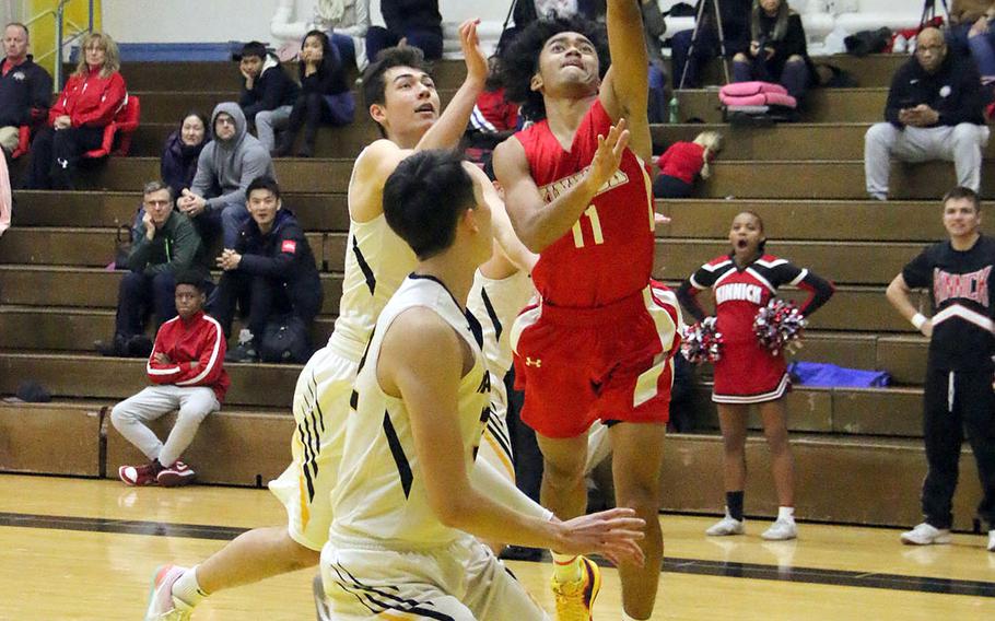Nile C. Kinnick's Chris Watson drives for a layup against American School In Japan defenders during Saturday's rematch of last year's Far East Division I and combined tournament finals. The defending D-I champion Red Devils edged the defending combined champion Mustangs 70-62.
