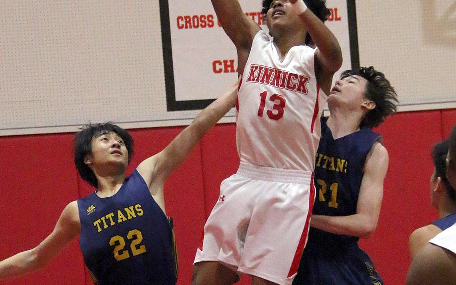 Nile C. Kinnick's Kaine Roberts shoots between St. Mary's  Lucas Wainwright and William Masuyama during Tuesday's Japan boys basketball game. The Red Devils won 51-30.