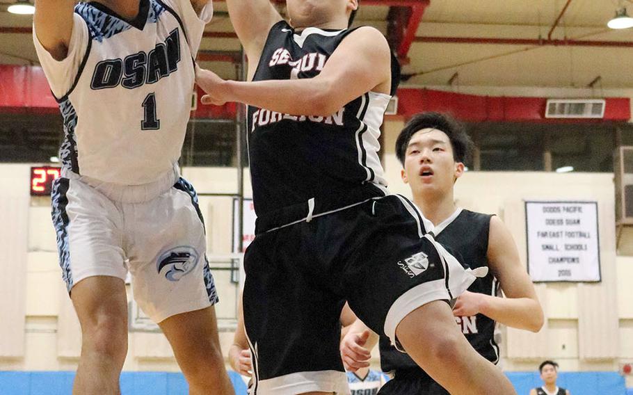 Osan's Leo Legaspi and Seoul Foreign's Joonhee Lee try to get the handle on the ball during Wednesday's Korea boys basketball game. The Cougars won 78-59.