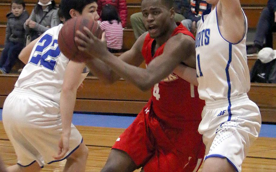 Nile C. Kinnick's Roderick Bell knifes between Christian Academy Japan's Koji Matsuoka and Ty Hall during Tuesday's Japan boys basketball game. The Red Devils won 89-68.