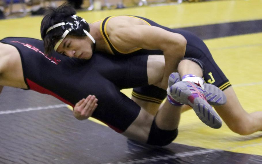 American School In Japan's Egan Salder gets the advantage on Nile C. Kinnick's Ethan Hamilton at 148 pounds during Tuesday's Japan wrestling dual meet. Sadler won by 14-5 decision and the Mustangs won the meet 42-20.