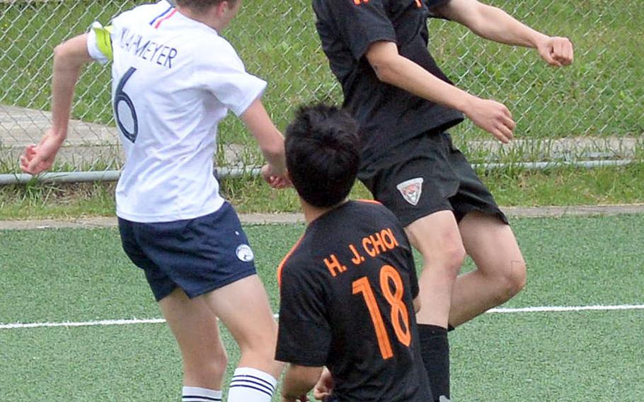 Seoul International's Archie Lee heads the ball against Osan's Ryan Klapmeyer during Friday's Korea boys soccer Plate Tournament at Osan Air Base. The host Cougars won 3-0.