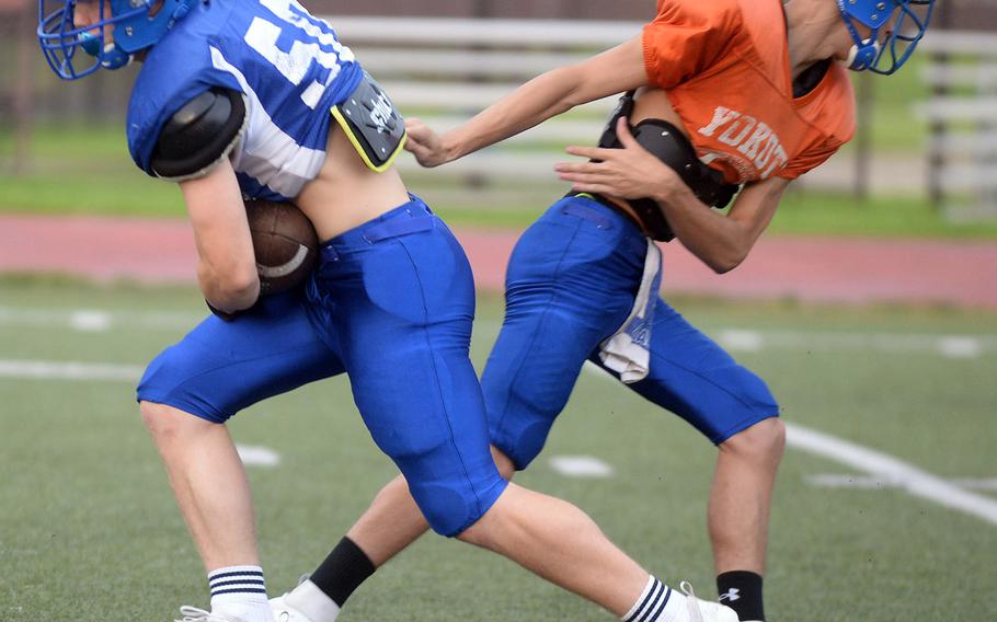 Returning running back Ethan Smith takes a handoff from quarterback Chris Jones, new to Yokota via Nebraska, in a preseason practice.