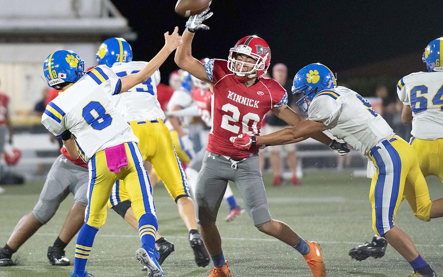 Nile C. Kinnick's Anthony Santos, rushing Yokota quarterback Brody Choate's throw, had seven tackles for the Red Devils.