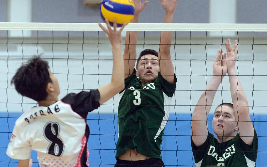 Osan's Timothy Petrae tries to tap the ball against Daegu's Charles Lyons and Chase Lamar during Saturday's Korea boys volleyball match. The Warriors won in straight sets.