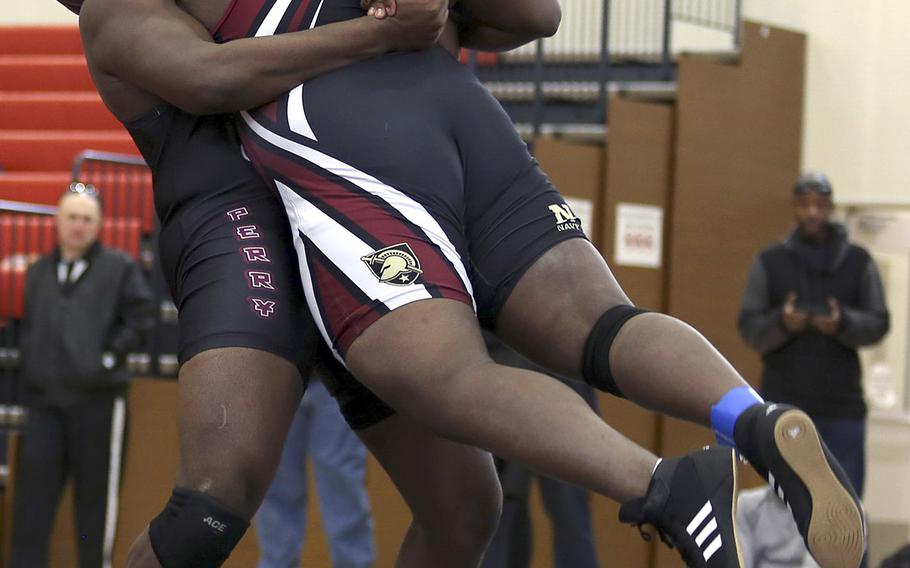 Two-time defending Far East heavyweight champion Marshall China, lifts Zama's Solace Mack during Saturday's DODEA-Japan dual meet tournament. China won by technical fall 10-0, but the Trojans beat the Samurai 33-19.