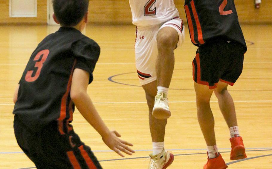 Nile C. Kinnick's James Mincey grabs the ball between E.J. King defenders Cameron Reinhart and James Meacham during Friday's DODEA-Japan boys basketball game. The Red Devils won 78-71.