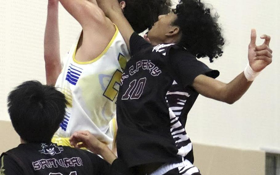 Yokota's Connor Rowan snags a rebound in front of Matthew C. Perry's Shion Fleming and Joseph Andres during Saturday's boys basketball game. The Samurai edged the Panthers 43-42.