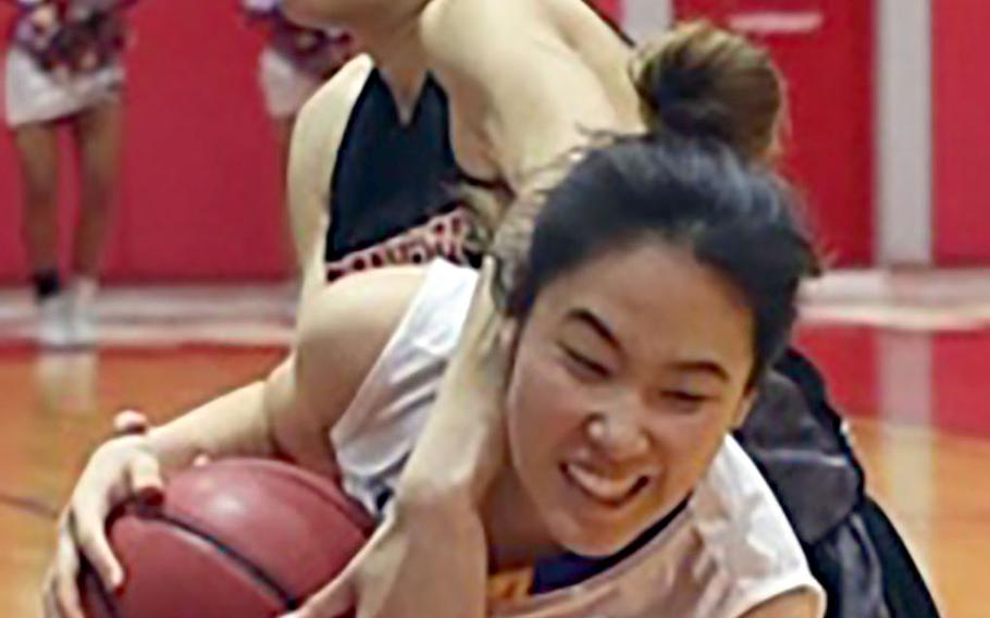 Christian Academy Japan's Kim Yeon-joo and Nile C. Kinnick's Ernestina Roberts tie up the ball during Thursday's Kanto Plain girls basketball game. The Knights won 46-28.