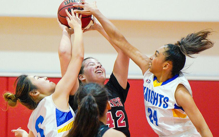 Nile C. Kinnick's Madelyn Gallo gets sandwiched by Christian Academy Japan's Hyeon Seo Kwon and Mari Mosaku during Thursday's Kanto Plain girls basketball game. The Knights won 46-28.