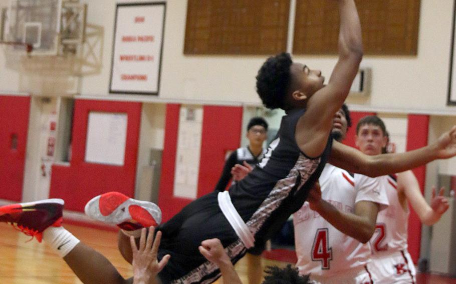 Zama's Keshawn McNeill loses his purchase as he puts up a shot against Nile C. Kinnick's James Mincey and Darryl Williams during Tuesday's DODEA-Japan/Kanto Plain boys basketball game. The Trojans won 64-61.