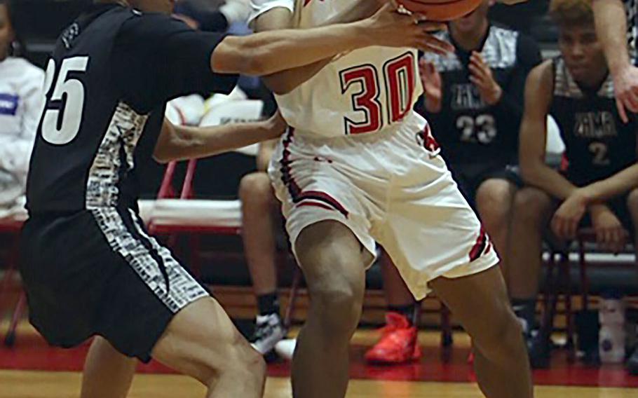 Nile C. Kinnick's Shawn Williams looks to pass against Zama's Murray Gillerson during Tuesday's DODEA-Japan/Kanto Plain boys basketball game. The Trojans won 64-61.