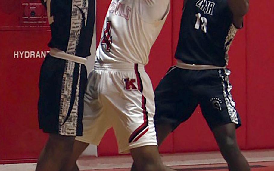 Nile C. Kinnick's Darryl Williams gets sandwiched by Zama's Kalil Irby and Chandler Platt during Tuesday's DODEA-Japan/Kanto Plain boys basketball game. The Trojans won 64-61.