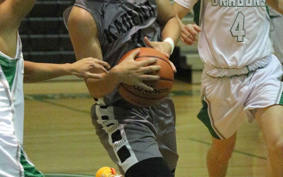 Kadena's Casey Cox drives past Kubasaki's Mason Taylor during Friday's Okinawa boys basketball game. The Panthers won 65-31 and clinched the season series from the Dragons.