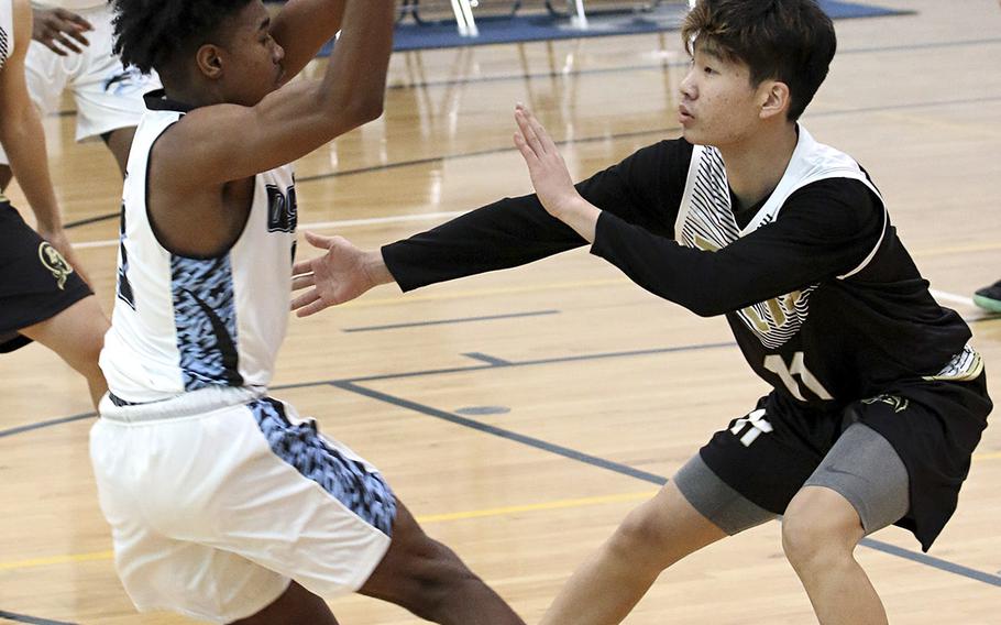 Osan's Bryson Goldsmith gets pressured by Taejon Christian's Josh Yun during Saturday's Korea Blue boys basketball game. The Cougars won their first game in six tries 67-44 over the Dragons.
