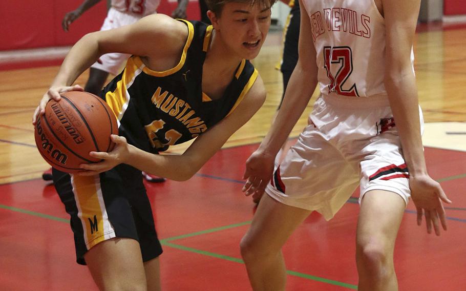 American School In Japan's Max Murakumo-Mases looks for room against Nile C. Kinnick's Ethan Yuska during Saturday's Kanto Plain boys basketball game. The Mustangs won 75-46.