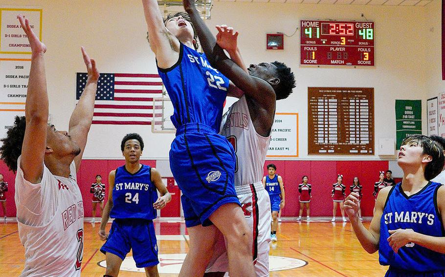 St. Mary's Lucas Wainwright leaps for a rebound against Nile C. Kinnick's Corey Hollingsworth during Tuesday's Kanto Plain boys basketball game. The Titans won 74-54.