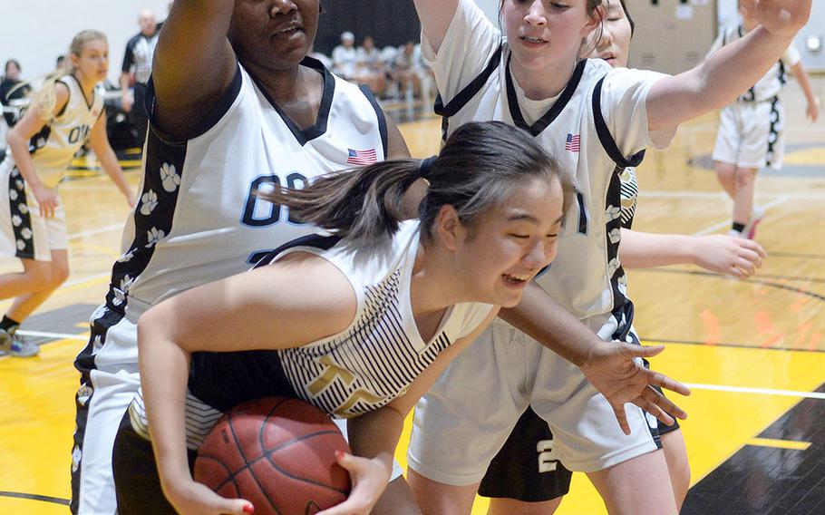 Taejon Christian's Amy Choi gets hemmed in by Osan's Cor'Rhyia Henry and Sadie Liddell during Tuesday's Korea Blue girls basketball game. The Dragons won 34-30.