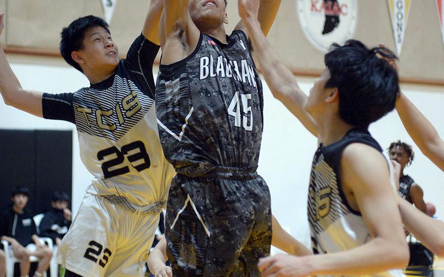Humphreys' Collin Metcalf skies for a shot between Taejon Christian's Jaylen Koo and Yisoo Han during Wednesday's Korea Blue boys basketball game. The Blackhawks won 78-30.
