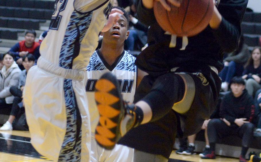 Osan's Matthew Cornelius and Taejon Christian's Josh Yun scuffle for the ball during Tuesday's Korea Blue boys basketball game. The Cougars won 58-53, their second straight win, both against TCIS.